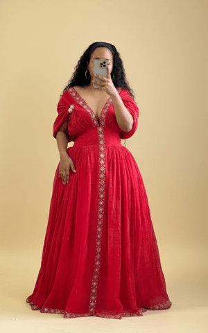 A vibrant red, floor-length Ethiopian traditional dress with intricate white embroidery